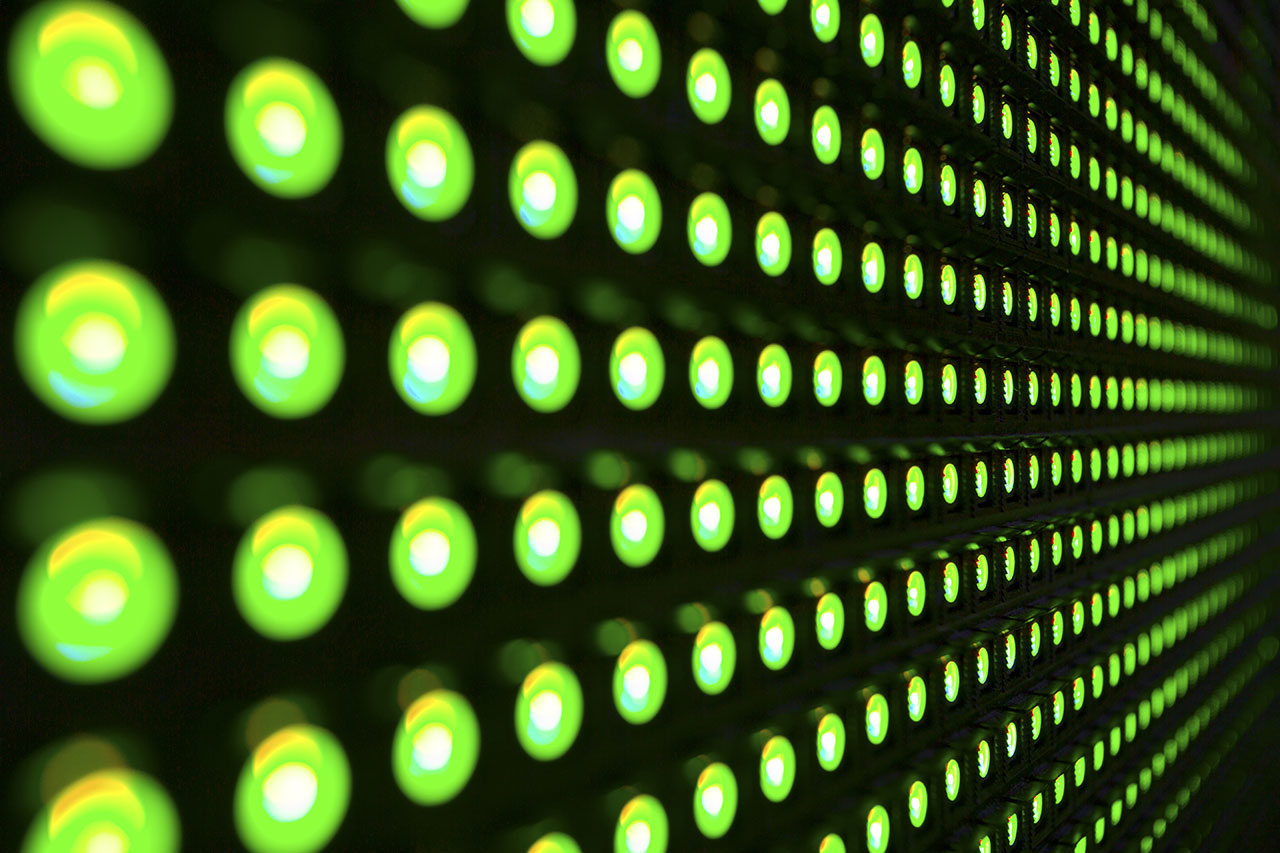 Eine grüne Wand mit zahlreichen Lichtern, der Energieeffizienz und Innovation in der Technologie von Parasigna symbolisiert.
